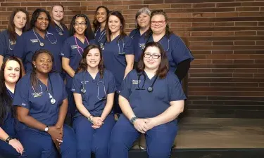 Group of LPN to RN students in blue scrubs posing for photograph